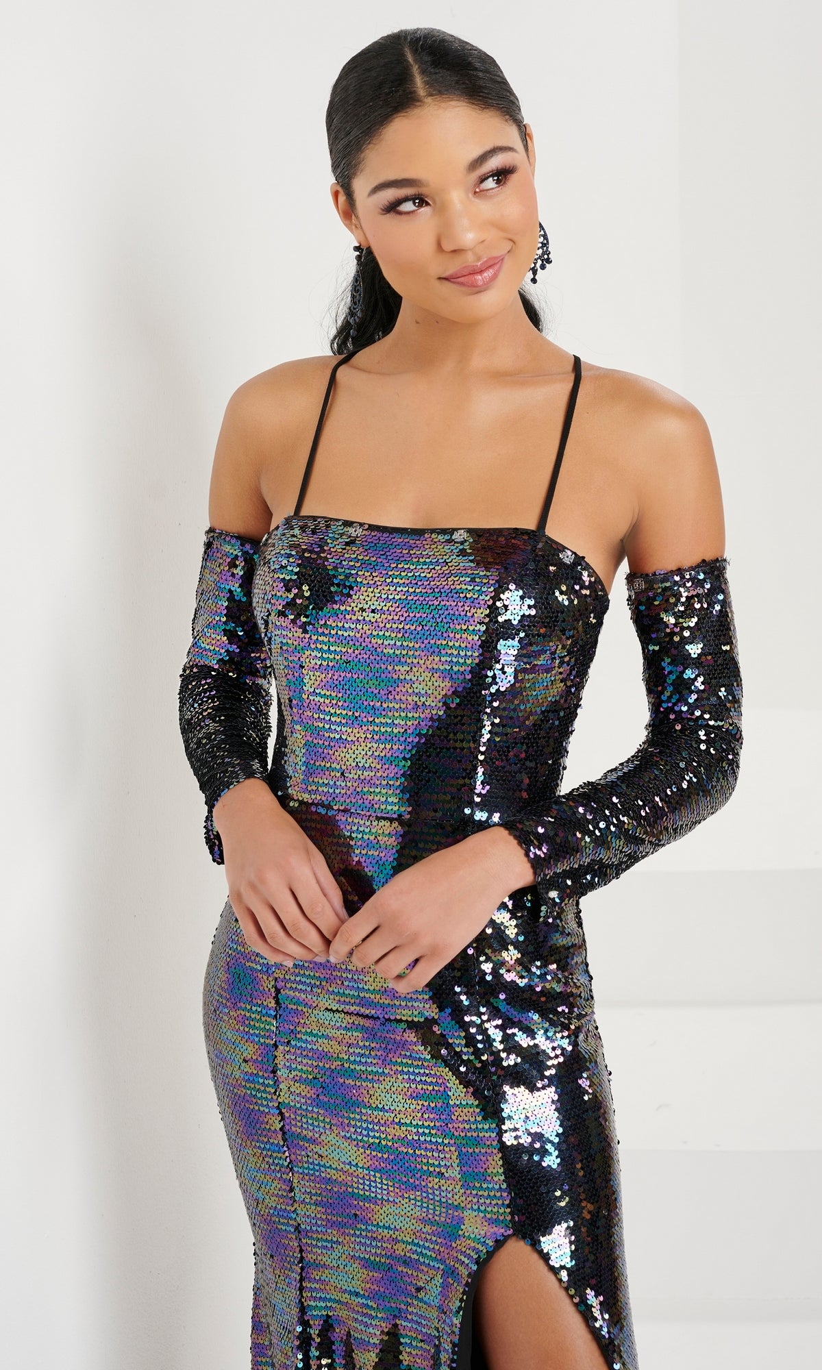A woman wearing the Long Prom Dress 16070 by Tiffany—a shimmery sequin formal gown with thin straps, open lace-up back, and matching long sleeves—stands indoors, looking to the side.